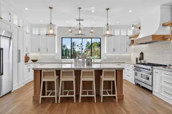 a kitchen with stainless steel appliances granite countertop a sink a stove and a wooden floors