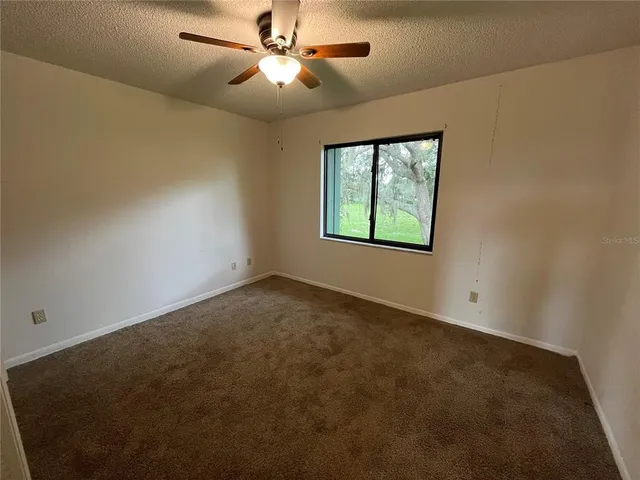 an empty room with a window and a fan