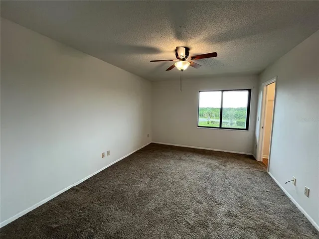 an empty room with windows and ceiling fan