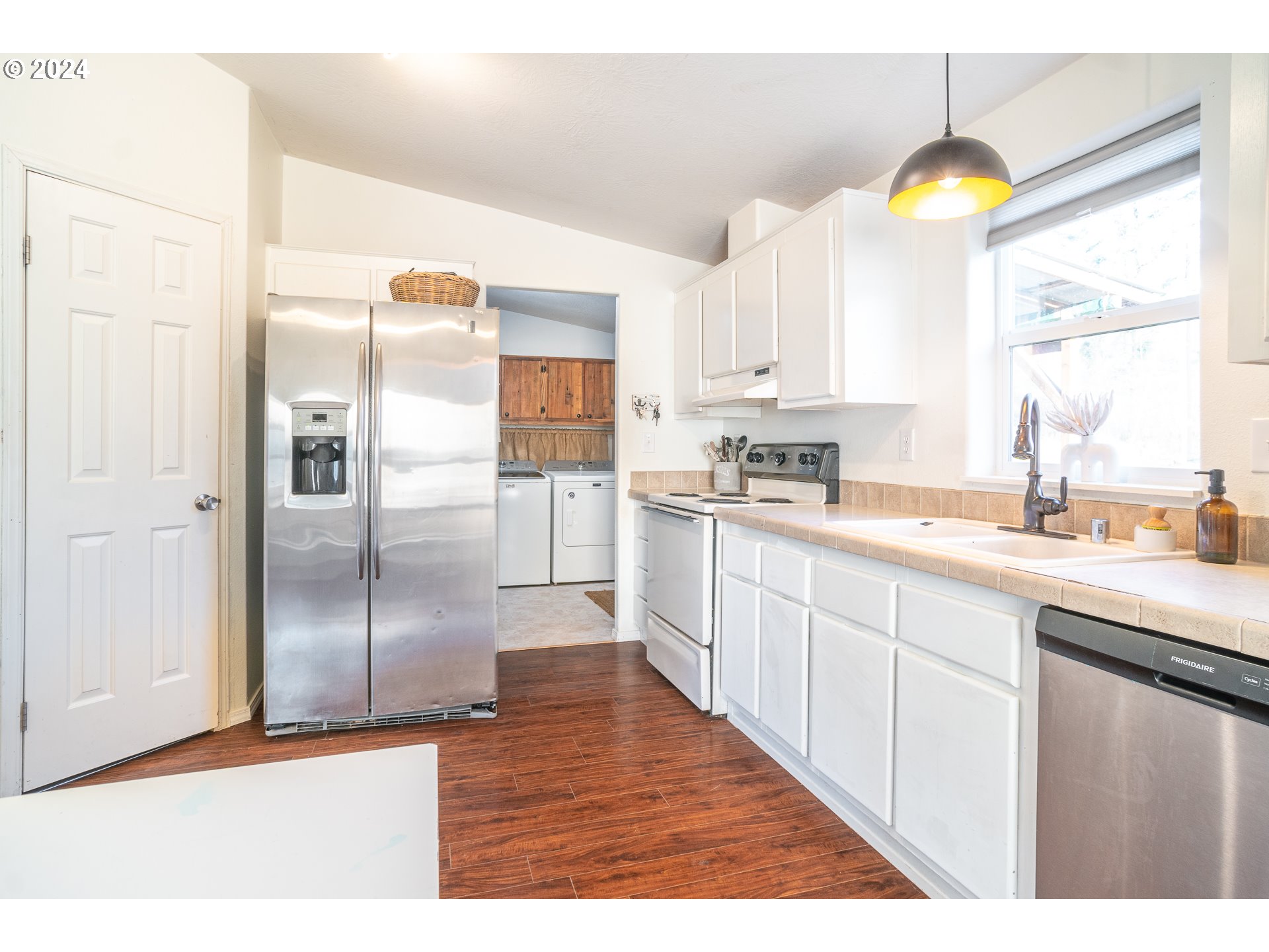 22233 Northeast Basket Flat Road Battle Ground, WA 98604 - Photo 35 of 46 a kitchen with stainless steel appliances granite countertop a refrigerator a sink a stove and white cabinets with wooden floor
