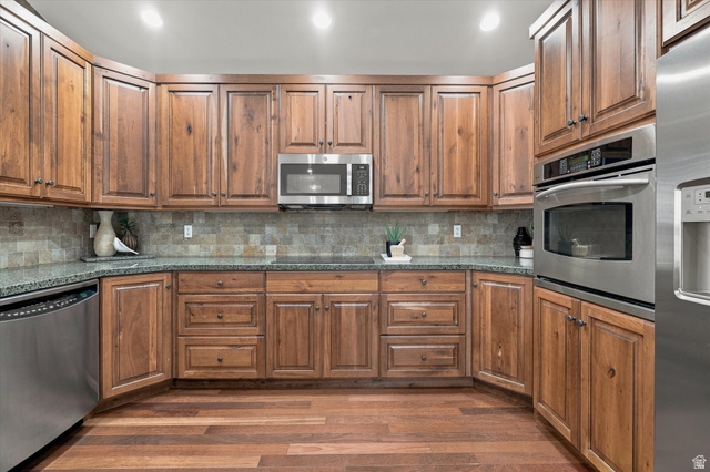 689 Apple Drive Logan, UT 84321 - Photo 11 of 52 Kitchen featuring wood cabinetry, stainless steel appliances, dark countertops, and a tile backsplash