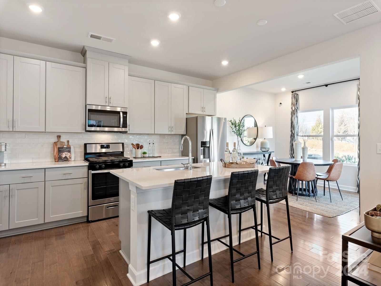 3840 Backwater Street Concord, NC 28027 - Photo 4 of 23 a kitchen with kitchen island granite countertop a dining table chairs and white appliances