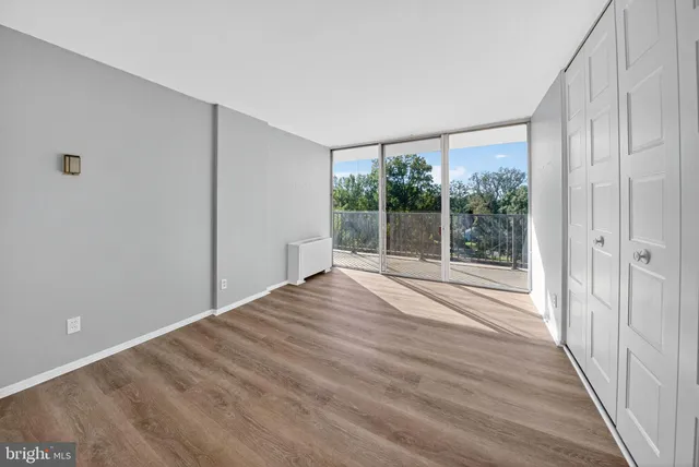 a view of empty room with wooden floor and fan