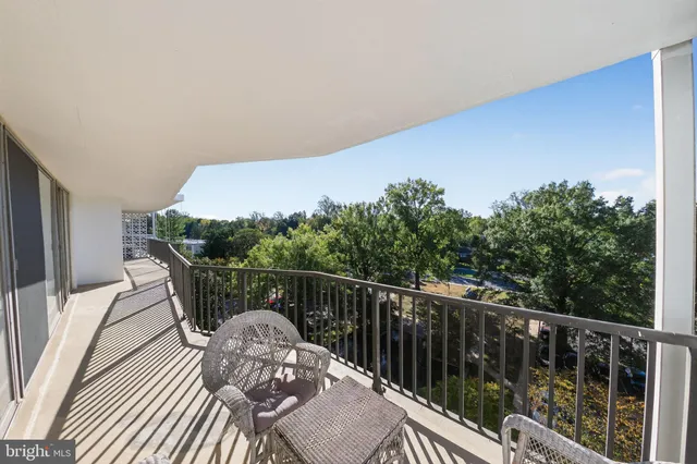 a balcony with wooden floor table and chairs