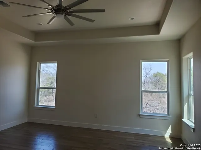 a view of an empty room with wooden floor and window