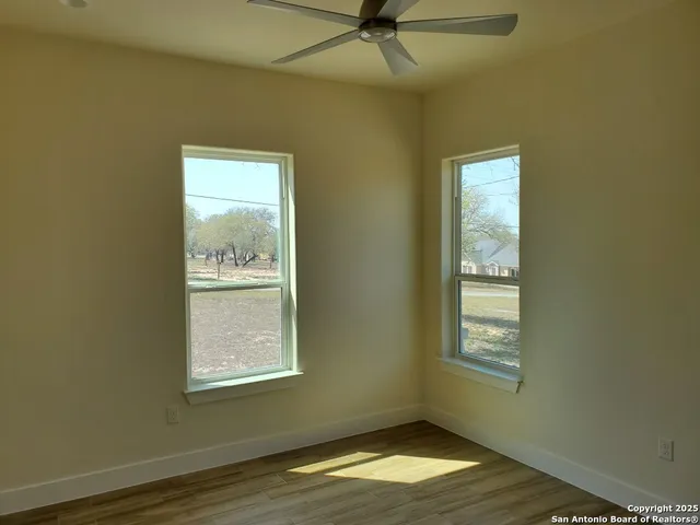 a view of an empty room with wooden floor and a window