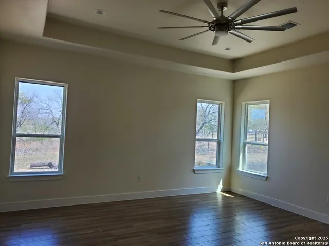 a view of an empty room with wooden floor and window