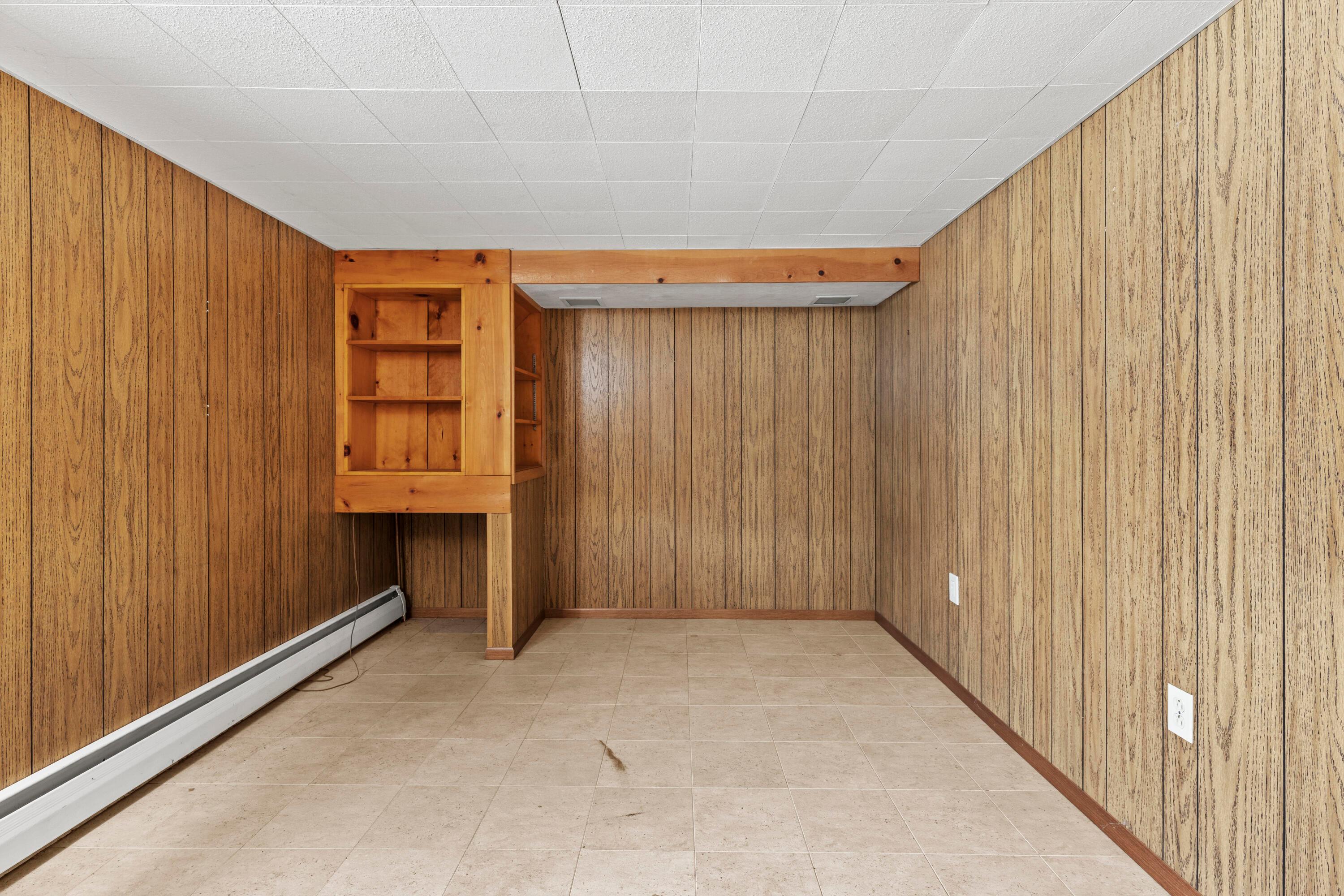 6982 Lee Road Westerville, OH 43081 - Photo 42 of 71 • Neutral vinyl flooring • Paneled walls • Built-in book shelves • Acoustic ceiling tiles