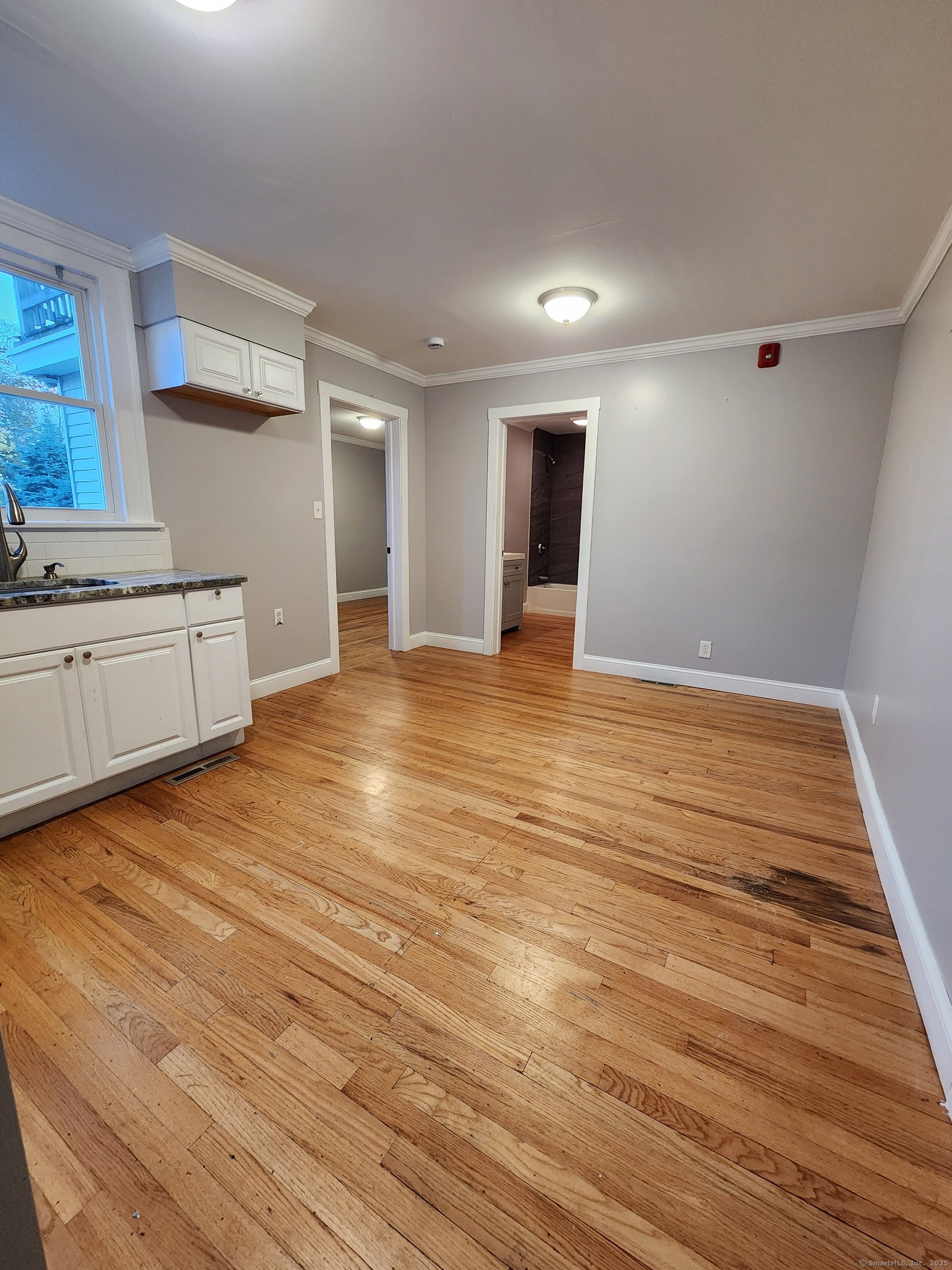a view of an empty room with window and wooden floor