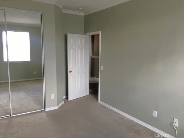 a view of an empty room with closet and a window