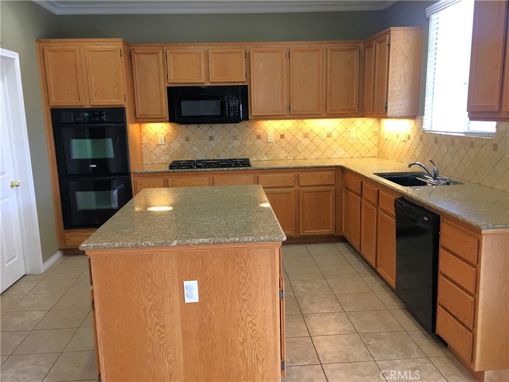 15213 Hawk Street Fontana, CA 92336 - Photo 2 of 20 a kitchen with granite countertop a stove top oven a sink a counter space and cabinets