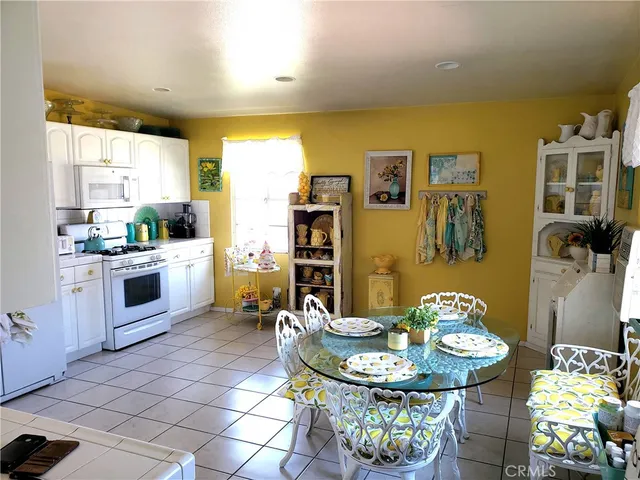 a kitchen with stainless steel appliances granite countertop a sink a stove a dining table and chairs