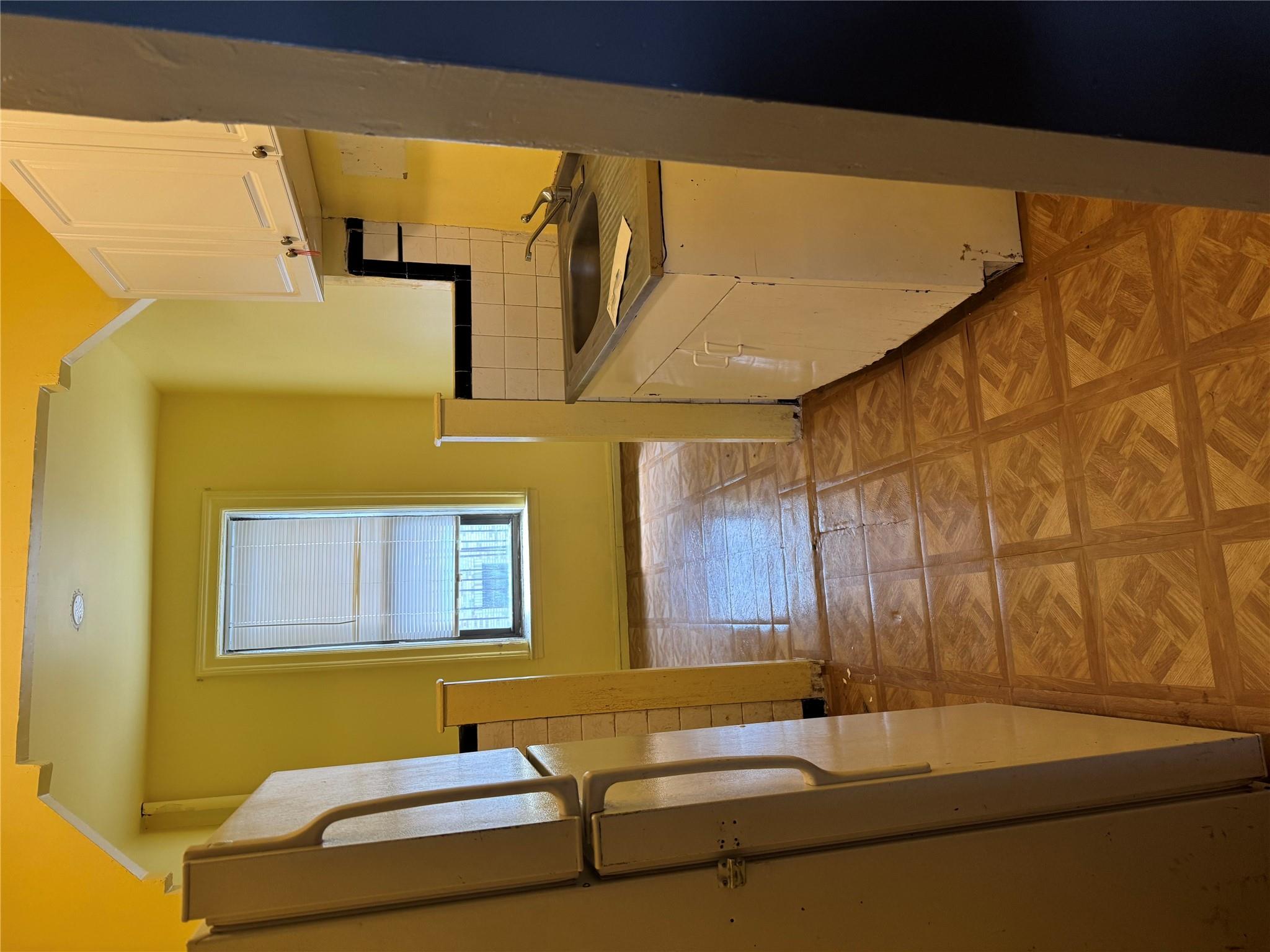 Kitchen featuring fridge, white cabinetry, backsplash, and dark countertops