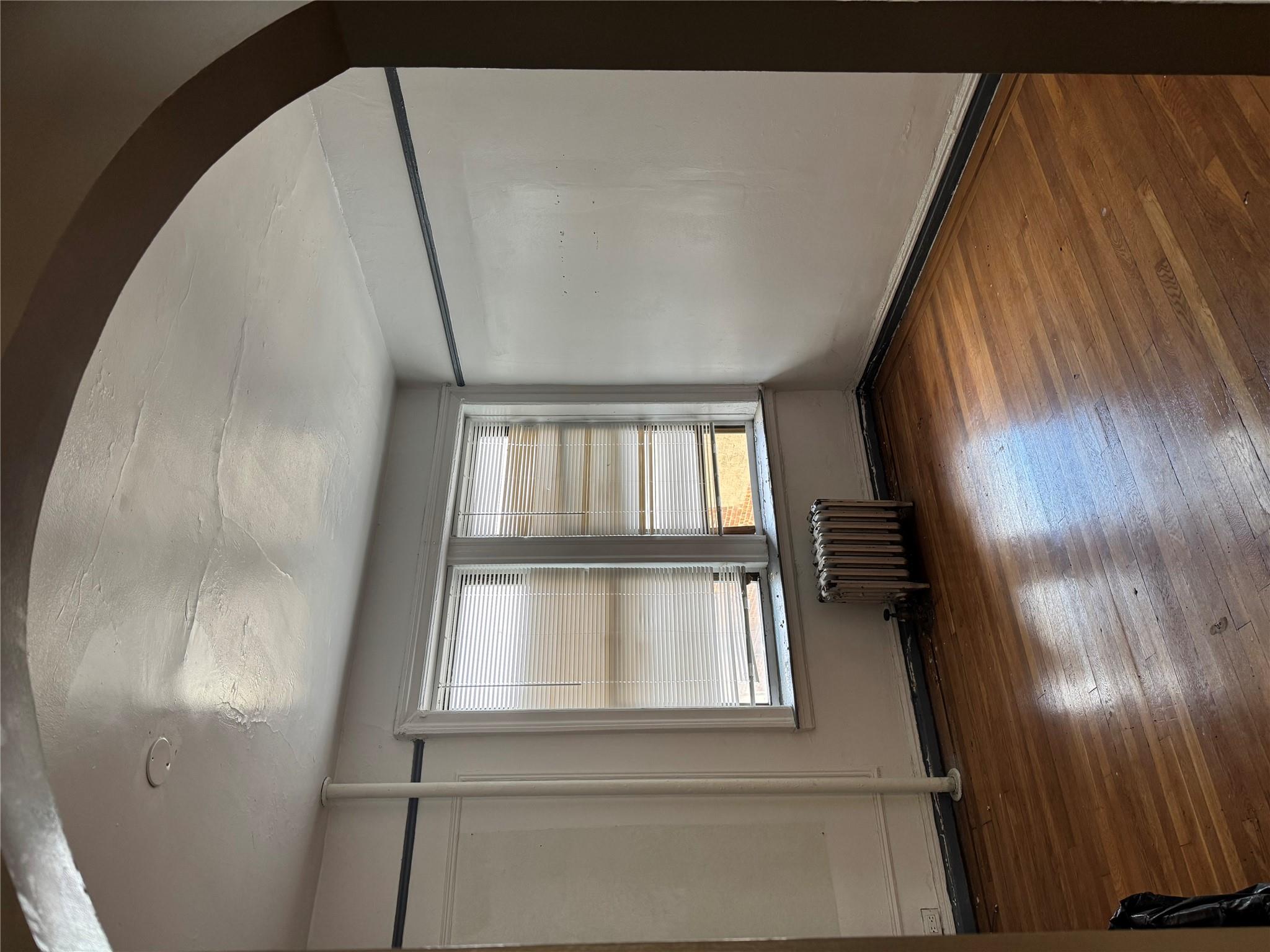 2922 Barnes Avenue, Unit 3A Bronx, NY 10467 - Photo 3 of 12 Unfurnished room featuring radiator, arched walkways, and wood-type flooring