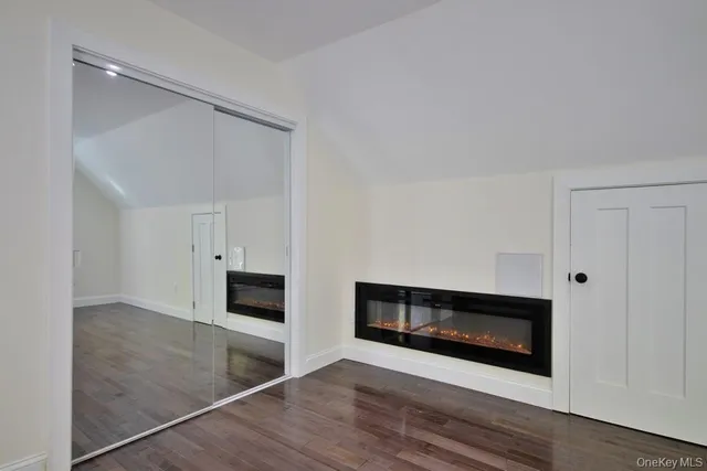 a view of an empty room with wooden floor fireplace and a window