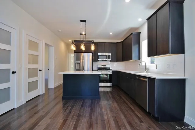 a large kitchen with stainless steel appliances kitchen island granite countertop a sink refrigerator and cabinets