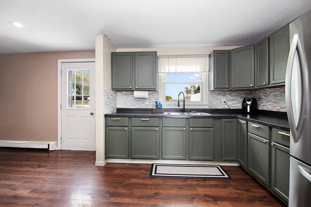 a kitchen with granite countertop a sink cabinets and wooden floor
