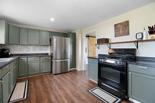 a kitchen with granite countertop a refrigerator and a stove top oven