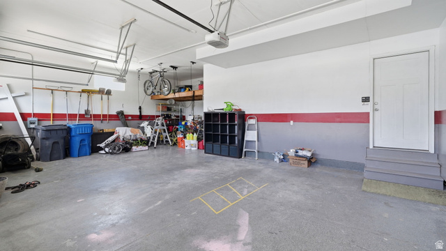 111 East Silver Oak Road Vineyard, UT 84059 - Photo 24 of 50 Spacious garage featuring a finished concrete floor, painted walls with a red accent stripe, an interior access door with steps, and overhead storage shelving
