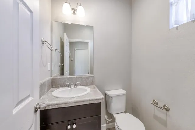 a bathroom with a granite countertop sink a toilet and a mirror