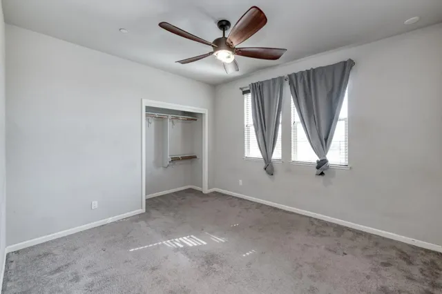 an empty room with windows and ceiling fan