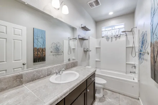 a bathroom with a granite countertop sink mirror toilet and bathtub