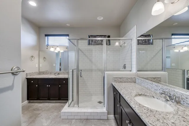 a bathroom with a granite countertop sink a mirror and shower