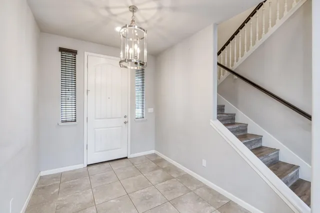 a view of a hallway with stairs and chandelier