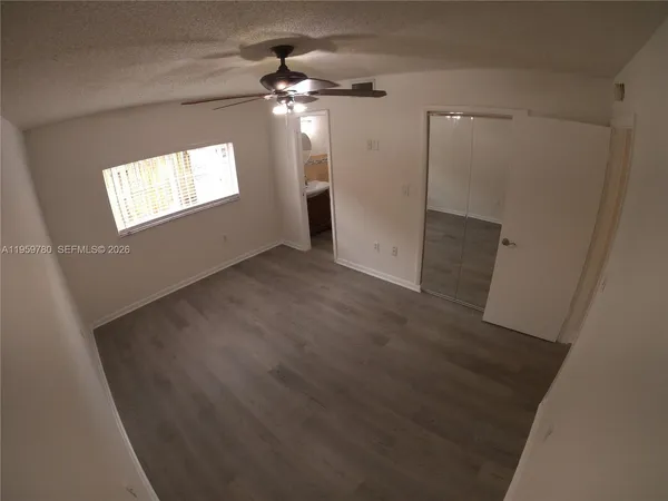 an empty room with wooden floor fan and windows