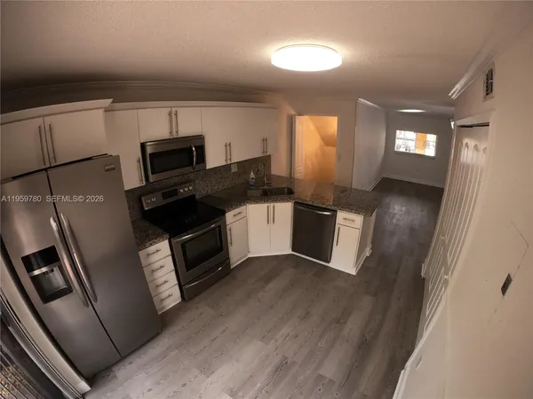 a kitchen with granite countertop a refrigerator stove and microwave