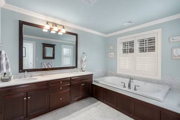 a bathroom with a tub double sink mirror and