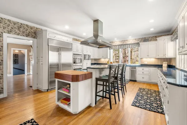 a kitchen with stainless steel appliances a stove a sink dishwasher and a dining table with wooden floor