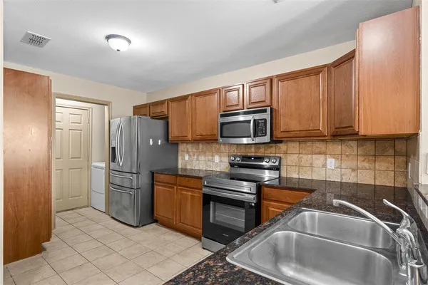 a kitchen with stainless steel appliances granite countertop a refrigerator stove and sink