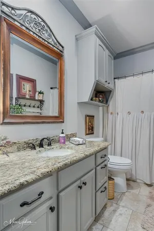 a bathroom with a granite countertop toilet sink and mirror
