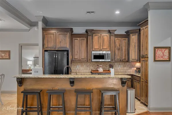 a kitchen with kitchen island granite countertop a table chairs microwave and cabinets