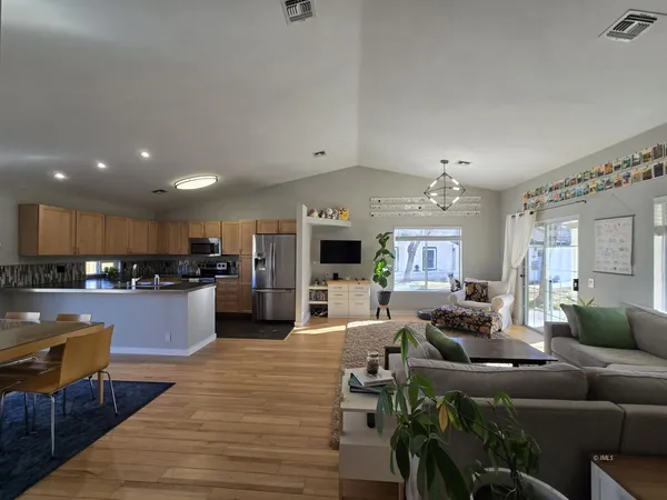 a living room with furniture kitchen view and a wooden floor
