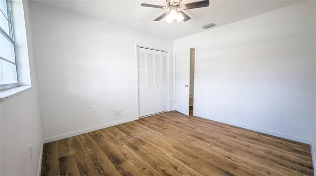a view of empty room with wooden floor and fan