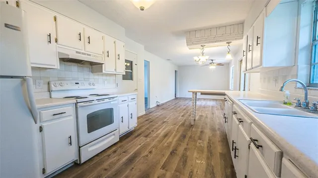 a kitchen with cabinets wooden floor and stainless steel appliances