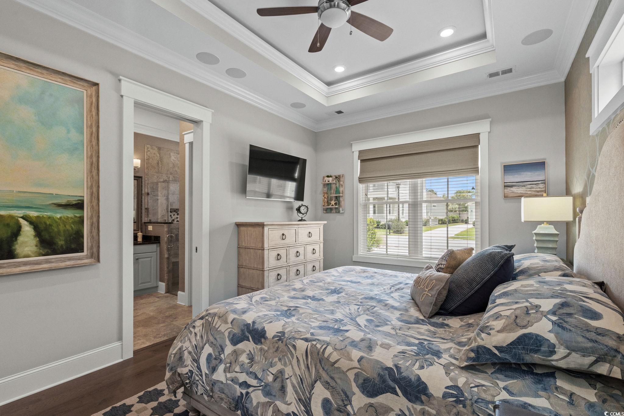 8245 Sandlapper Way Myrtle Beach, SC 29572 - Photo 19 of 40 Bedroom featuring multiple windows, dark wood-style floors, ornamental molding, a tray ceiling, and ceiling fan