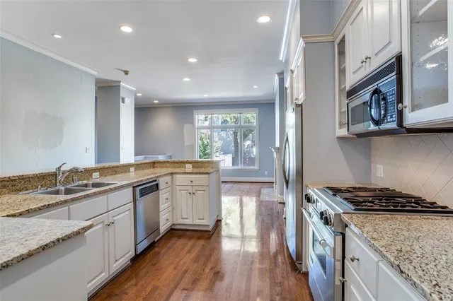 a kitchen with stainless steel appliances granite countertop a stove a sink and a microwave