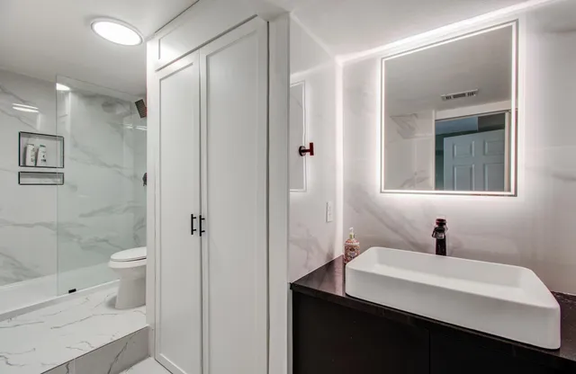 a bathroom with a sink a toilet a shower and a mirror