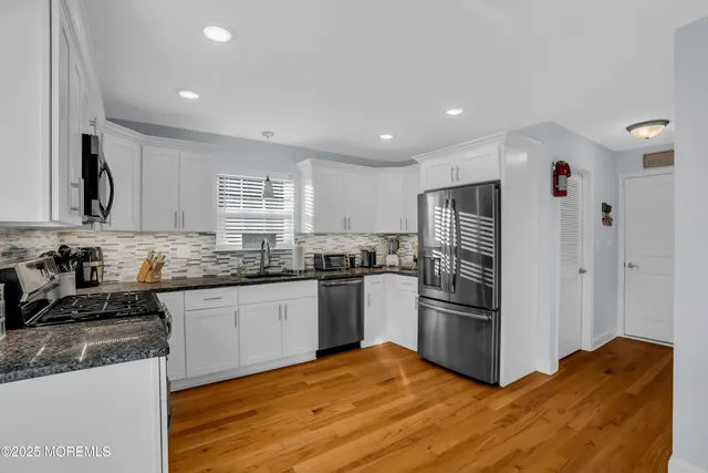 a kitchen with granite countertop a refrigerator and a stove top oven