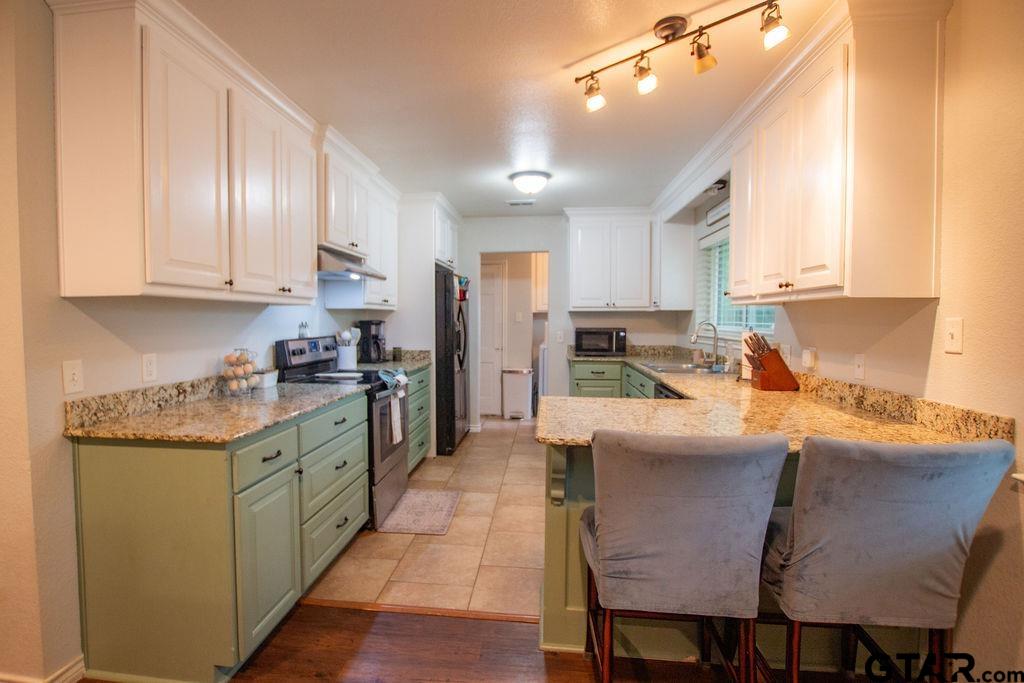 2110 Inwood Circle Tyler, TX 75701 - Photo 10 of 44 a kitchen with stainless steel appliances granite countertop a table chairs sink refrigerator and cabinets