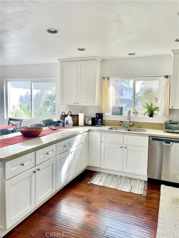 a large white cabinets with wooden floor and stainless steel appliances