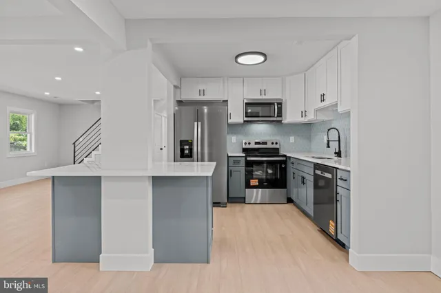 a kitchen with kitchen island white cabinets and stainless steel appliances