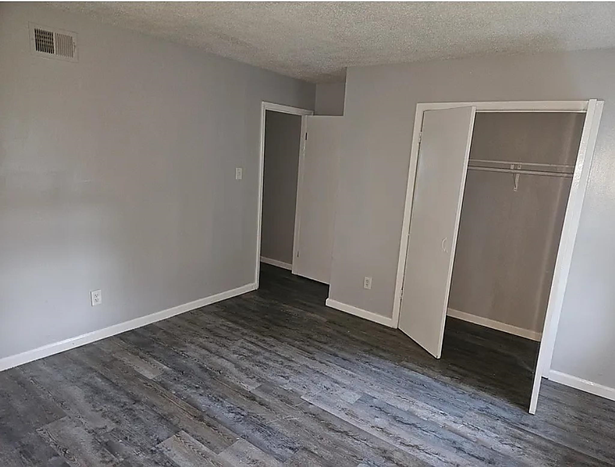 4444-4446 Sumners Wells Road Memphis, TN 38118 - Photo 8 of 8 Spacious room featuring wood-finish flooring, light gray wall paint, white baseboards, and a built-in closet with bi-fold doors