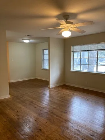 a view of an empty room with wooden floor and a window
