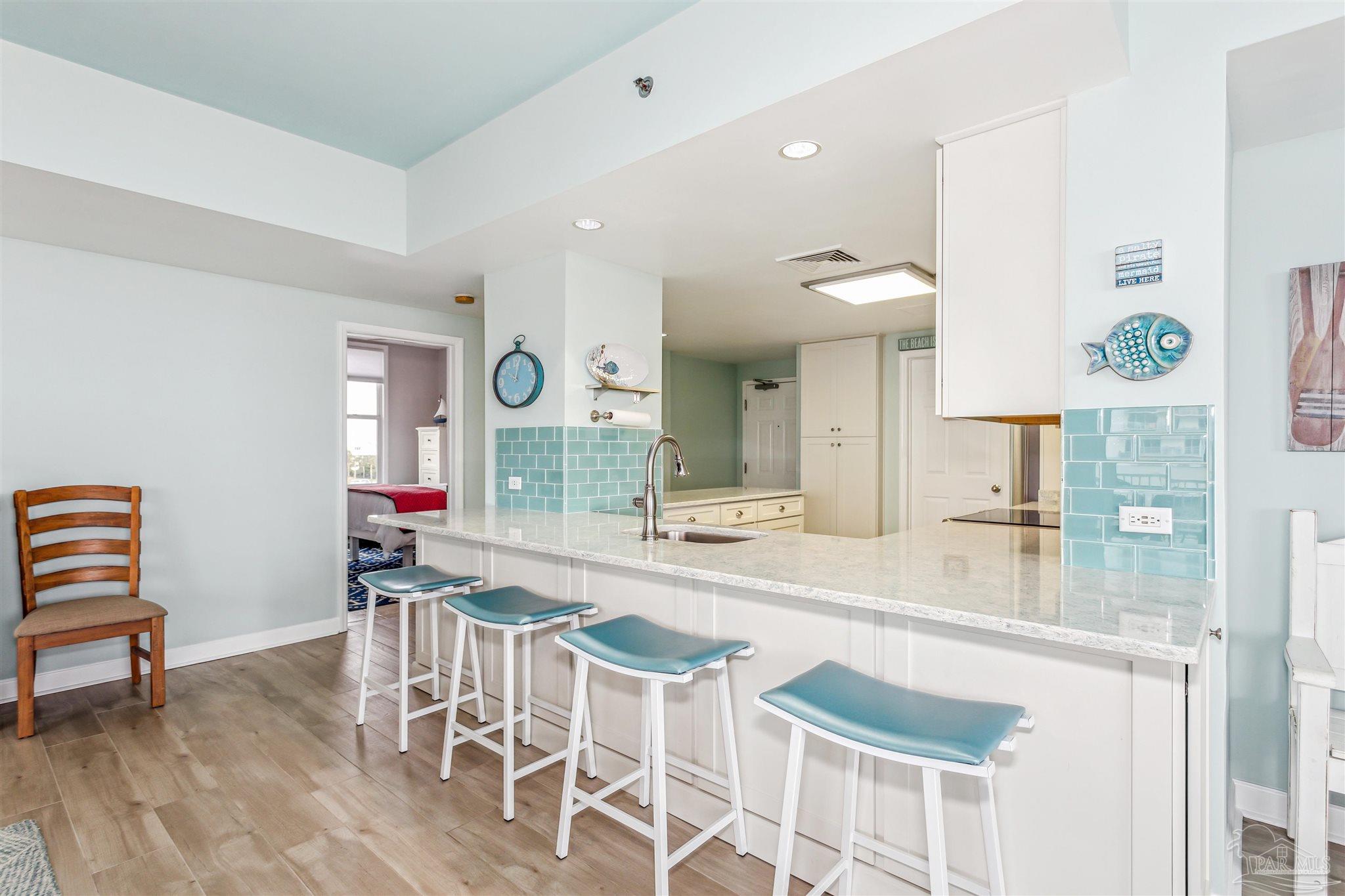 800 Fort Pickens Road, Unit 204 Pensacola Beach, FL 32561 - Photo 17 of 45 a kitchen with stainless steel appliances kitchen island granite countertop a table and chairs in it