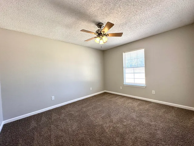 an empty room with windows and fan