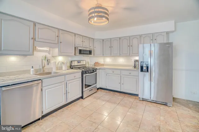 a kitchen with white cabinets stainless steel appliances and a window
